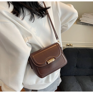 Detail of vintage dark brown leather crossbody bag featuring a golden cylindrical twist lock