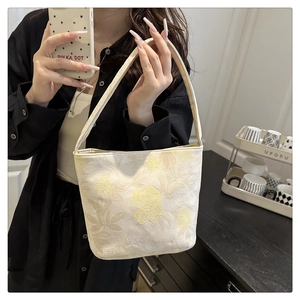 Detailed close-up of beige floral jacquard tote bag with elegant handheld strap