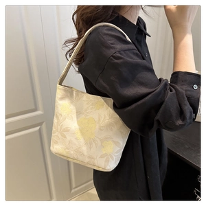 Détail de la texture du sac cabas en jacquard beige avec motifs floraux brodés jaunes