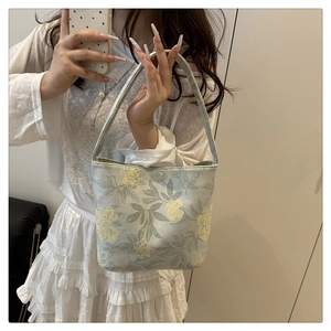 Detail of floral embroidery on a light blue canvas tote bag with yellow flower patterns