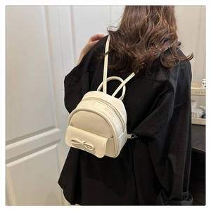 Detail of a creamy white bow mini backpack with fine PU leather texture and metal zipper