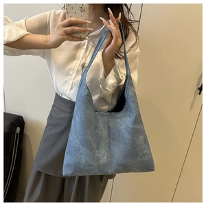 Detail of blue large capacity tote bag with wide integrated shoulder strap and washed texture