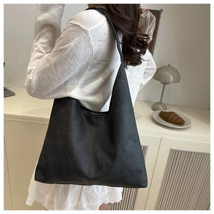 Minimalist black matte tote bag with vertical stitching shown in a lifestyle home setting