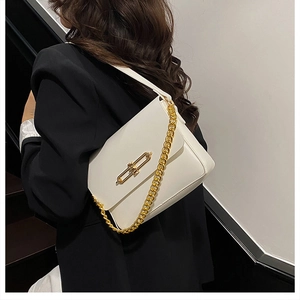 Gros plan d'un sac en cuir blanc avec chaîne dorée et fermoir sur un mannequin