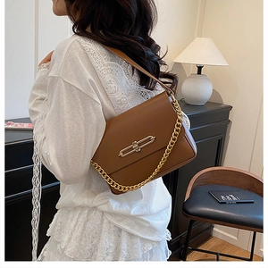 Détail d'un sac à bandoulière en cuir marron avec chaîne dorée et fermoir métallique chic