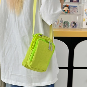 Neon green nylon crossbody bag with drawstring and zipper shown in a daily lifestyle setting