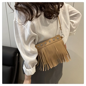Detail view of khaki crossbody bag featuring stylish silver rivets and long tassel fringe