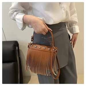 Dettaglio della borsa a tracolla marrone con frange, borchie metalliche e trama in pelle