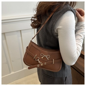 Detalle de bolso hobo vintage marrón con lazo dorado y hebilla metálica sobre modelo