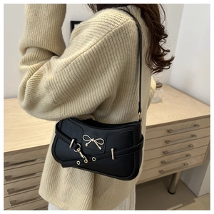 Detailed view of black PU leather shoulder bag with gold metal bow and adjustable strap
