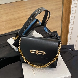 Minimalist black flap crossbody bag with gold buckle and chain on mirror background