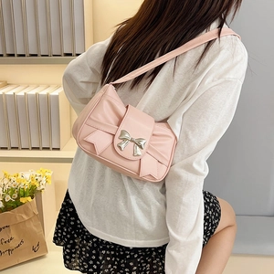 Chic pink shoulder bag with large bow and silver buckle shown on a female model