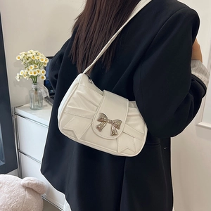 Chic white pleated shoulder bag with large bow and metal butterfly buckle on a model