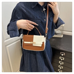 Detail of two-tone Kelly bag in brown and cream with gold twist lock on denim dress