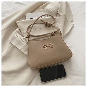 Detail of a beige bow-knot handbag on a blazer, showing smooth faux leather texture