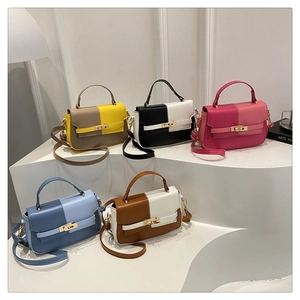 Five bicolor crossbody bags in various colors displayed on white geometric platforms