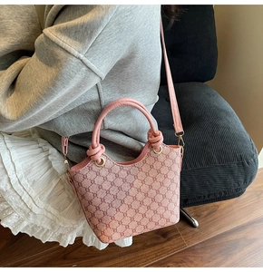 Détail du sac seau rose avec imprimé chaîne et poignée nouée porté à l'épaule