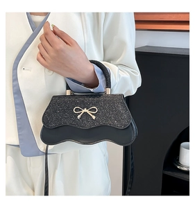 Dettaglio del fiocco dorato su borsa in pelle con paillette e bordo ondulato chic