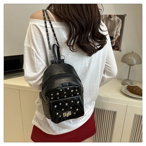 Detail of mini black leather backpack featuring quilted pattern, silver studs and chain straps