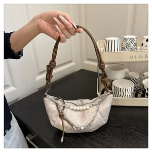 Dettaglio borsa denim a mezzaluna con perle bianche, catena argento e tracolla annodata