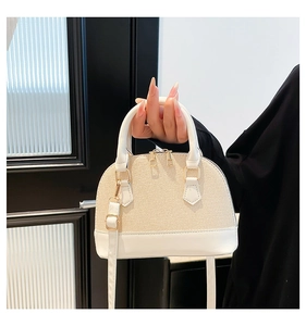 Detail of elegant beige shell bag featuring woven texture and gold dual zipper hardware