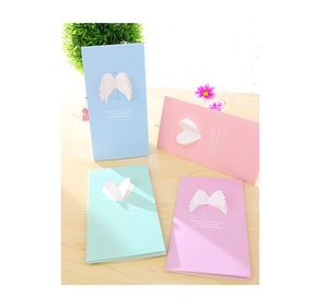 Détail de cartes pop-up 3D ailes et cœur en couleurs pastel sur table en bois