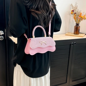 Borsa a tracolla glitter rosa con patta ondulata e fiocco dorato sulla modella