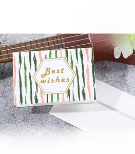 Detail of greeting card with Best Wishes gold foil text and white envelope on rock surface