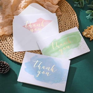 Detailed view of watercolor thank you cards with gold foil lettering and matching envelopes