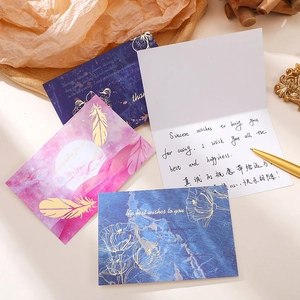 Gold foil greeting card set with feathers and flowers, featuring envelopes and gold pen