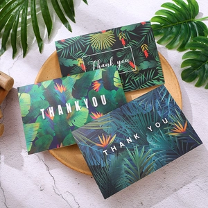 Three tropical floral thank you cards with envelopes on a round wooden tray and marble surface
