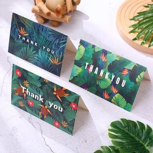 Detailed view of tropical themed thank you cards on a white marble surface backdrop