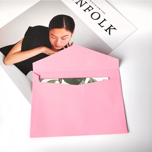 Pink kraft paper envelope with floral invitation card on minimalist Kinfolk background