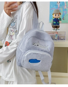 Dettaglio dello zaino in peluche blu chiaro con ricamo a squalo e spalline grigie regolabili