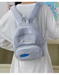 Dettaglio dello zaino a squalo in peluche grigio con morbida trama e ricamo