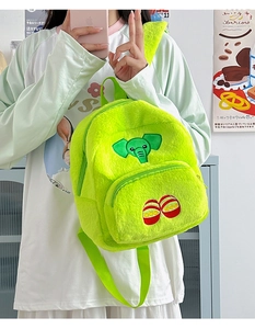 Dettaglio dello zaino di peluche verde neon con ricamo a elefante e texture morbida