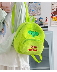 Dettaglio mini zaino in peluche verde neon con ricamo a elefante e consistenza morbida