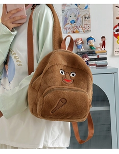 Dettaglio di uno zaino in peluche marrone con ricamo viso eccentrico e consistenza morbida