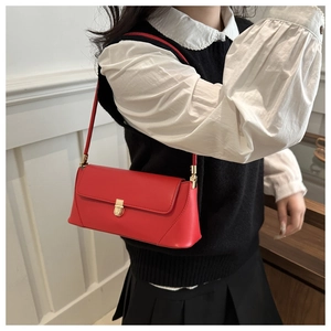 Detail of red baguette bag with smooth texture and golden metal clasp on a female model