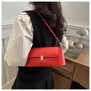 Side view of a vibrant red baguette bag worn by a model in a minimal interior