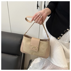 Dettaglio della borsa a sella beige con trama in pelle scamosciata e fiocco d'oro