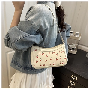 Detailed view of white leather underarm bag featuring vibrant red cherry print on model