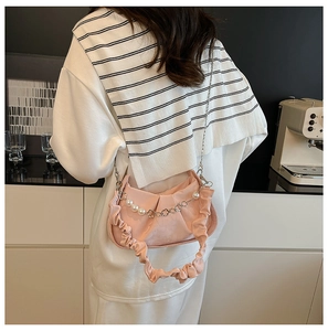 Detailed view of pink pleated shoulder bag with decorative pearl and floral metal chain