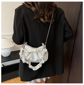 Detail of silver pleated cloud bag featuring elegant pearl and metal chain straps