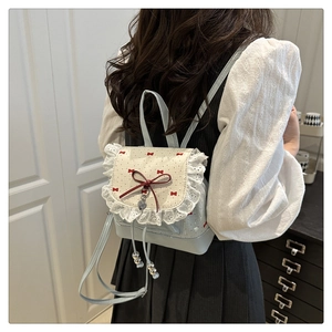 Detail of light blue mini backpack featuring white lace trim and red bow heart charms