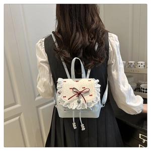 Rear view of a model wearing the mini ballet-style backpack with red bow patterns
