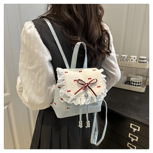 Detail of a balletcore mini backpack with red bow prints and white lace trim detail