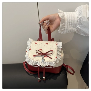 Detail of red bow patterns and white lace trim on the sweet style backpack flap