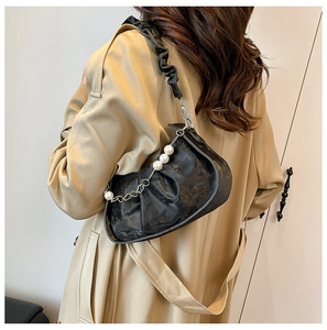 Detail of black pleated cloud bag with pearl chain accessory and wide shoulder strap