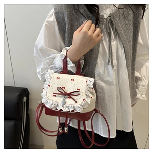 Detail of lace edges and red bow on a polka dot mini backpack with heart charm